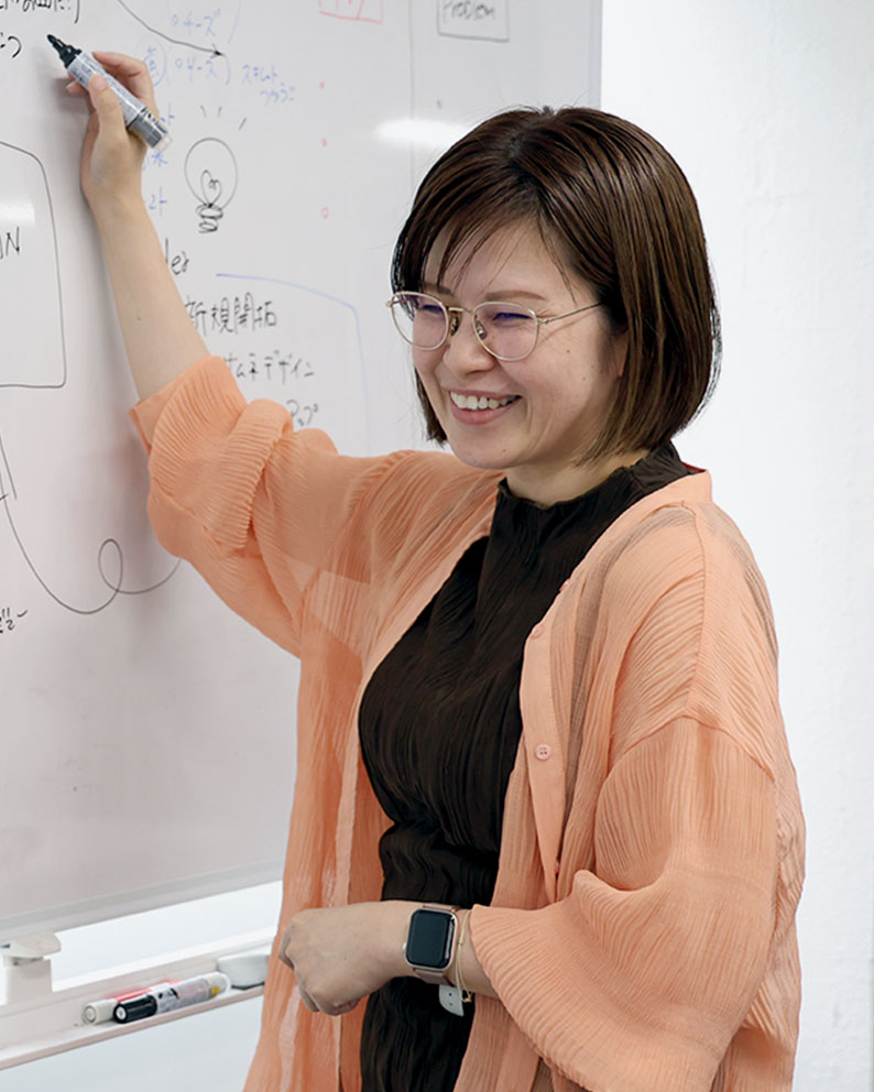 ホワイトボードに説明を描くサンクスラボの女性社員