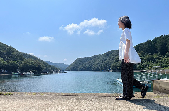 青い空と入江を背に海沿いを歩く社員