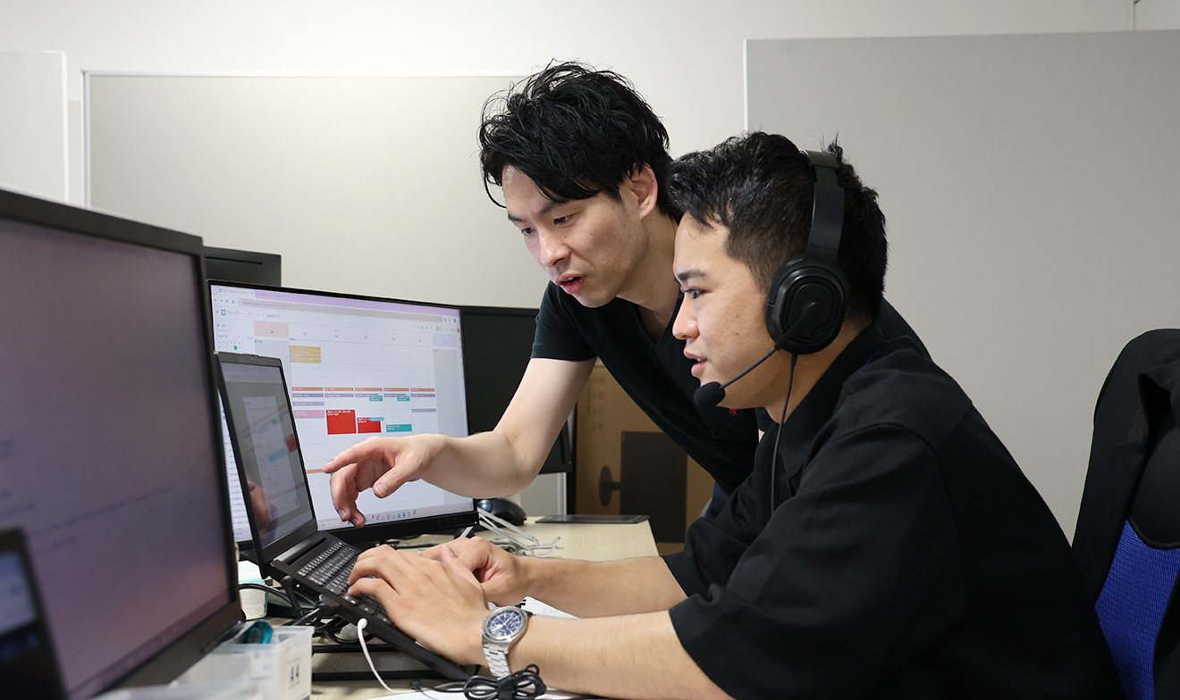 モニターを指差す人と、そのモニターをみながらキーボードを操作する人