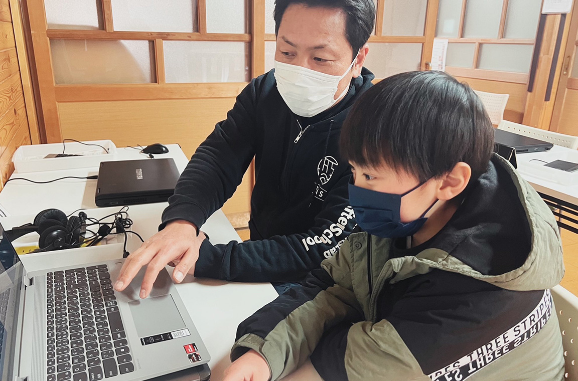 障がいのある児童にパソコンの使い方を教えるサンクスラボの社員