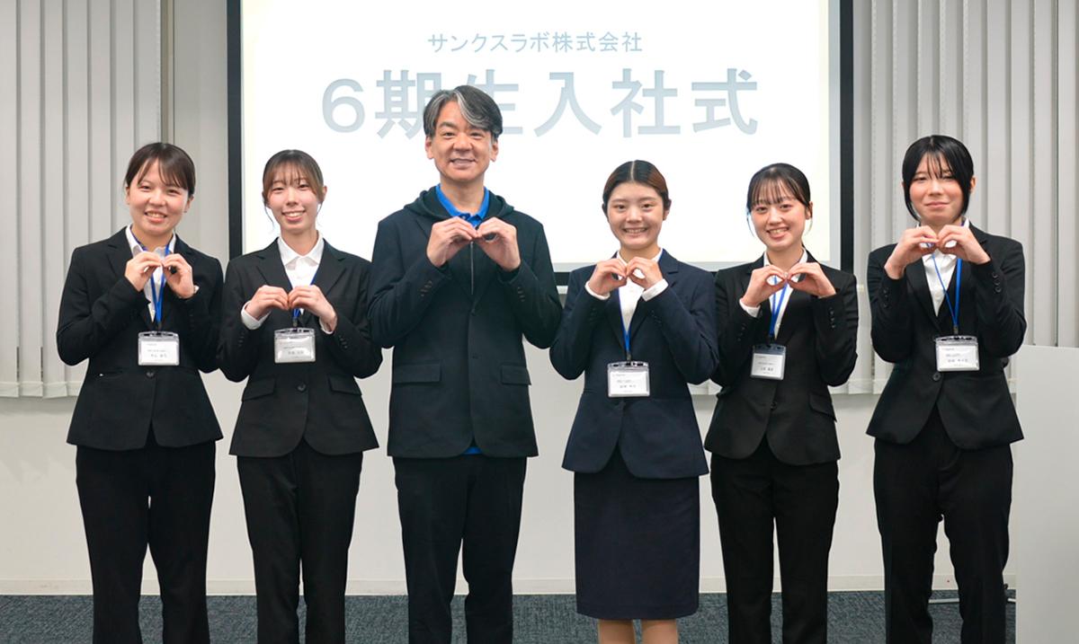 横一列に並び両手でサンクスラボの無限マークを作る新卒社員5名と代表